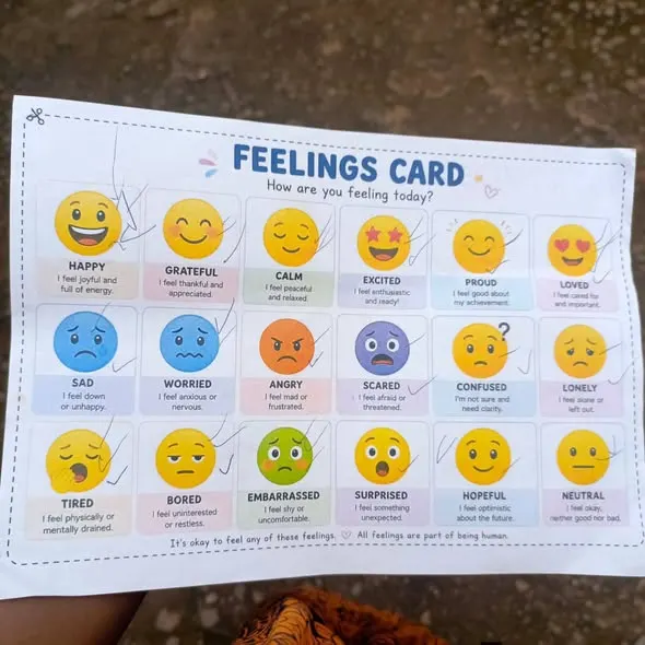 A printed feelings card showing eighteen emotions, from happy and grateful to worried and lonely